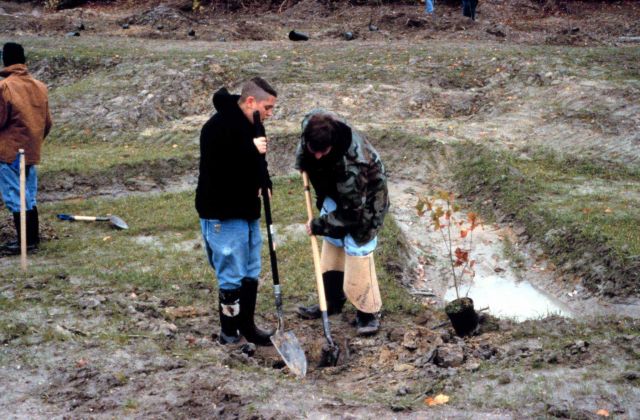 Two students dig a hole in preparation to plant potted wetland species at the restoration site. Picture