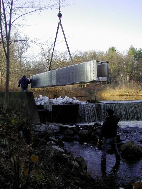 The crane lowers the first section into place, it is just about to be dropped into the notched dam. Picture