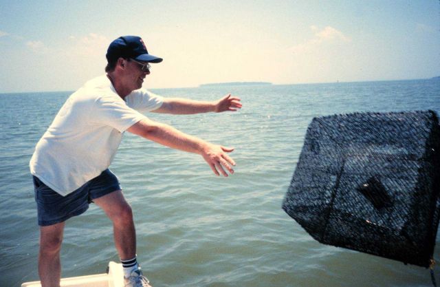 Chris Doley of NOAA sets a crab pot at a reference site, Coaches Island is in the distance. Picture