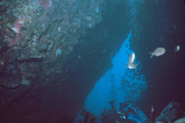 Divers in a passage through the rocks. Picture