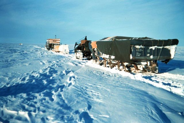 A cat train on the move across the tundra Moving equipment and supplies from Barter Island to Tigvariak Island Black object is a boat hull for use in  Picture