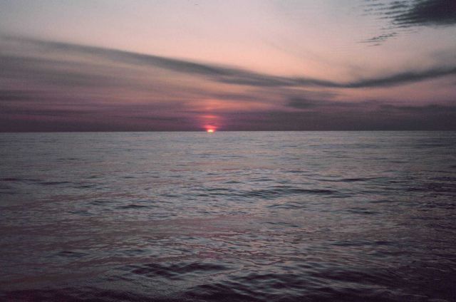 Sun peeking over the oceanic horizon at sunrise Picture