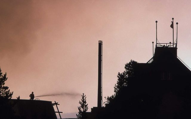 Silhouette of firefighter spraying water on Old Faithful Inn Picture