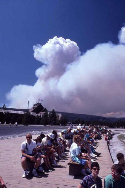 Visitors waiting for eruption of Old Faithful Geyser with dense plume of smoke rising behind Old Faithful Inn Picture