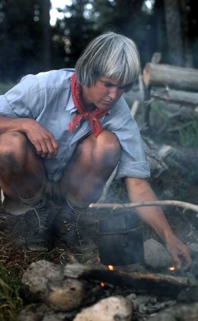 Woman tending campfire at backcountry campsite Picture