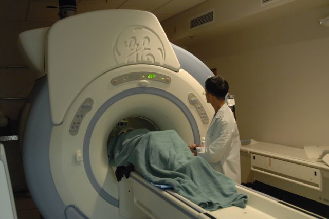 Technician checks MRI machine with patient Picture