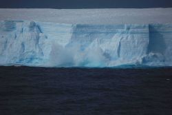 A wave crashing on a large tabular iceberg Image