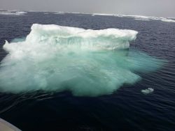A small ice berg with its greater mass of ice visible below the surface. Image