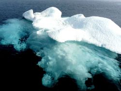 A small ice berg with its greater mass of ice visible below the surface. Image