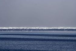 Parallel patterns in the waters of the Beaufort Sea with ice floes and a pressure ridge in the distance. Image