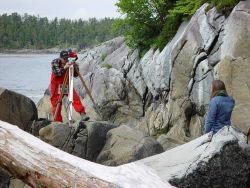 A NOAA surveyor is leveling from a tidal staff (top of staff visible to left of observer's right leg) Image