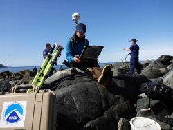 Senior Survey Technician Brandy Geiger with Trimble satellite positioning system determining location of tide gage site as other members of work crew  Image