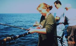 Young woman reeling in her first fish of the day. Image