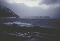 A large fishing vessel leaving Dutch Harbor on a gray, cold, windy evening. Image