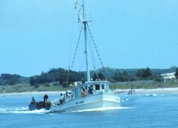 A small menhaden vessel with auxiliary boats being towed astern Image