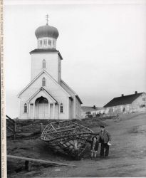 Frame of bidarra boat with Aleut man and his small child. Image