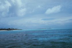 A low lying atoll with a navigation aid on a smaller outlying island. Image