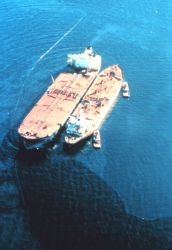 EXXON VALDEZ aground on Bligh Reef being lightered to reduce oil spillage and lighten ship to get off reef. Image
