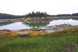 A rocky islet reflected in the low tide waters. Image