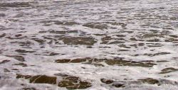 A foam flecked wave runs up on the Cape Hatteras shore. Image