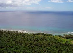 Looking down over the Guam jungle to the reef and surf far below. Image