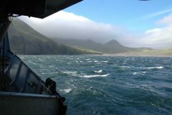 Fog blowing over the island while a williwaw stirs up the near shore waters. Image