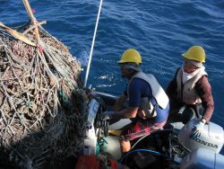 Derelict net debris being removed from inflatable boat and onto deck of CASITAS. Image