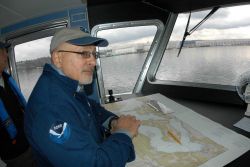 Dan Basta, director of the National Marine Sanctuary Program, standing at the chart table of the Flower Garden Banks Marine Sanctuary R/V MANTA during Image