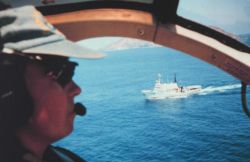 Lieutenant Debora Barr flying MD500 at San Benedicto Island with NOAA Ship DAVID STARR JORDAN below. Image