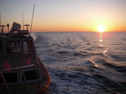 Looking astern at sunset from NOAA Ship THOMAS JEFFERSON over survey launch in davits. Image