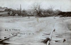 Water rushing over bent and broken railroad tracks. Image