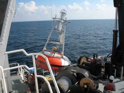 While the clouds approach and the TAO buoy streams aft with attached line, the deck crew of the NOAA Ship GORDON GUNTER move a second TAO to its pre-m Image