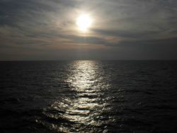 A gray colorless sunset with sunglint on the ocean surface Photo