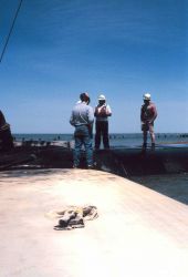 The crew discussing the filling of geotubes. Image