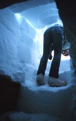 Looking out the entrance of the snow and ice shelter during survival training. Image
