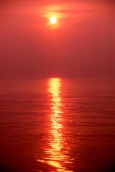 Orange sky and orange sea with a pillar of light reflecting off the ocean. Photo