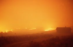 Wind driven sage (ground) fire approaching Blacktail cabin at night Image