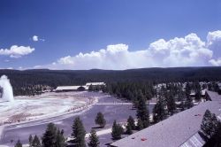 View of Old Faithful erupting with clouds of smoke in background Image